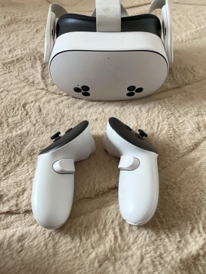 Vita VR-glasögon med handkontroller - Säljer ett par vita VR-glasögon med matchande handkontroller. Glasögonen har justerbart huvudband i tyg och svart insida för bekväm passform. Handkontrollerna är ergonomiska med knappar och styrspakar. Perfekt för gaming och VR-upplevelser. Den fungerar utmärkt. Jag har även startat om hela consollen så ni kan skapa ett nytt och eget konto och kommer även med en laddare
