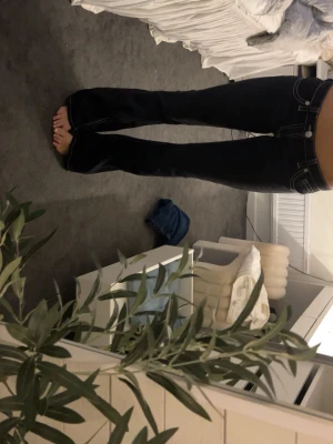 Svarta bootcut jeans med vita  sömmar (långa i benen)  - Säljer ett par svarta bootcut jeans med tydliga vita kontrastsömmar. Det är väldigt långa jag är 170 och de är långa på mig. Jeansen har låg midja och utsvängda ben, vilket ger en retro och trendig look. Perfekta för dig som vill ha en avslappnad men ändå snygg stil.