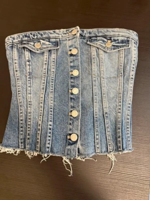 Jeans topp  - Säljer en snygg jeans topp med knappar framtill och rå kant nertill. 