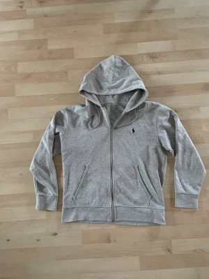 Grå ziphoodie Ralph lauren  - En grå ziphoodie från Ralph lauren. Använd fåtal gånger och i bra skick, den är köpt på plick men var för liten för mig.🤩🤩