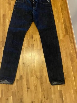 Mörkblå raka jeans från Replay - Säljer ett par mörkblå Timmar jeans från Replay. Jeansen har knäppning fram och detaljerade sömmar. Perfekta för dig som gillar en tidlös och stilren look. Aldrig använda