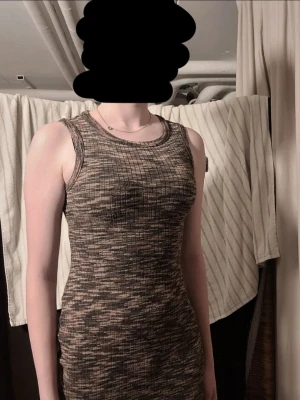 Ribbad ärmlös kortklänning brun - Säljer en ribbad, ärmlös kortklänning i bruna och beige toner. Klänningen har en kroppsnära passform och rund halsringning. Perfekt för dig som gillar en enkel men snygg stil.