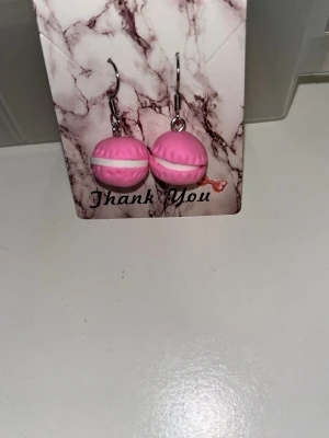 Rosa macaron örhängen  - Säljer ett par söta örhängen formade som rosa macarons med vita detaljer. Örhängens krokarna är i rostfritt stål. Finns i två andra färger Gröna och Lila