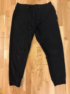 Ralph Lauren byxor - Säljer ett par svarta polo ralph lauren byxor som är ett set med koftan.  Storlek L. Byxorna har en avslappnad passform och sidofickor. Perfekta för chill dagar eller när du vill vara bekväm. Bra skick och inga stora defekter förutom sista bilden. 