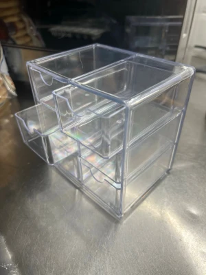 Transparent sminkförvaring med lådor - Praktisk och stilren sminkförvaring i genomskinlig plast med totalt fyra utdragbara lådor. Perfekt för att organisera borstar, smink eller småaccessoarer på sminkbordet. Den kompakta designen gör den enkel att placera i badrum eller sovrum.