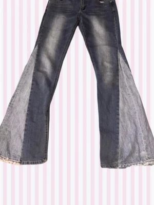 Blåa extrema utsvängda jeans - Säljer ett par blåa jeans med breda utsvängda ben och ljusa paneler på sidorna. Jeansen har klassiska fickor fram och bak samt kontrastsömmar. Materialet är denim i bomull och de har en cool retrovibe. Bra skick jag säljer pga för stor storlek