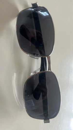 Silvriga fyrkantiga solglasögon - Skitcoola solglasögon med fyrkantiga, mörka glas och silvrig metallbåge.