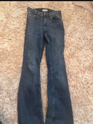 Mörkblå bootcut jeans - Säljer ett par mörkblå bootcut jeans med klassisk femficksdesign och normal midja. Jeansen har en snygg tvätt och raka ben som går ut lite nedtill för en retrovibe. Perfekta till sneakers eller boots.