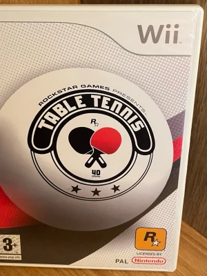 Table Tennis till Nintendo Wii - Table Tennis till Nintendo Wii är ett sportspel där du tävlar i bordtennis. Omslaget är vitt och grått med en stor pingisboll och två racketar i svart och rött. Spelet är licensierat av Nintendo och har stöd för flera spelare. Perfekt Skick