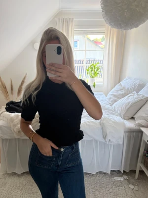 Svart basic t-shirt i bomull - En enkel svart t-shirt med rund hals och korta ärmar. T-shirten har en normal passform och är tillverkad i mjuk bomull, perfekt att matcha med jeans eller kjol för en clean look. T-shirten är tajt och ribbad. Knappt använd!