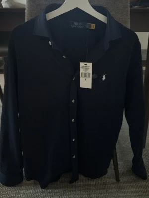 Mörkblå skjorta från Polo Ralph Lauren - Mörkblå skjorta från Polo Ralph Lauren. Köpt 1 vecka sedan bara testat och kunde ej ha Medium. Hör av er om ni undrar över något!