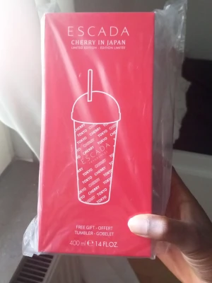 Escada Cherry in Japan tumbler - Säljer en limited edition Escada Cherry in Japan tumbler på 400 ml. Förpackningen är röd med vit text och har ett stilrent tryck av en bägare med lock och sugrör. Perfekt för dig som gillar snygga accessoarer till dryck.