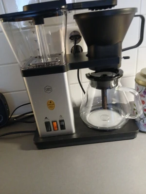Kaffebryggare med glaskanna - Säljer en stilren kaffebryggare i svart och silver med stor genomskinlig vattenbehållare och glaskanna. Bryggaren har två knappar på framsidan och en tratt för filter. Perfekt för dig som vill ha gott kaffe hemma.