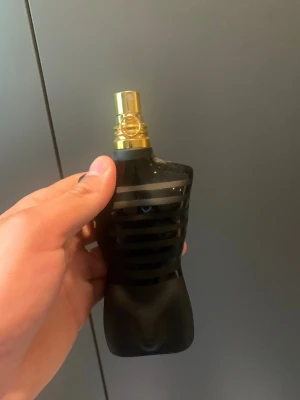 Jean Paul Gaultier le male le parfum  - Säljer en unik parfymflaska i svart frostat glas formad som en manlig torso med horisontella ränder. Flaskan har en guldfärgad spraykork och känns riktigt lyxig och cool att ha framme. Perfekt för dig som gillar snygg design på parfymflaskor.