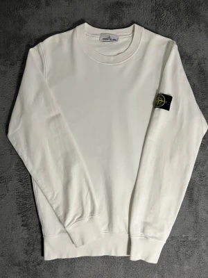 Stone Island – White Sweatshirt (L) - Classic Stone Island sweatshirt in clean white, featuring the iconic compass badge on the sleeve. Size L, fits well also for M. Length 73 cm, pit‑to‑pit 56 cm – relaxed and comfortable fit.  ✅ Condition: Excellent – no visible wear or stains 💯 Authenticity: 100 % genuine, can be verified via certilogo.com   📦 Shipping: Fast dispatch after purchase  This sweatshirt embodies Stone Island’s signature minimalist design and premium craftsmanship — durable, stylish, and timeless 🤍