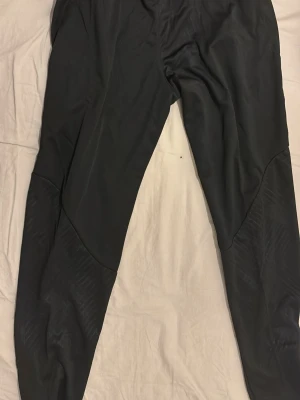 Svarta Nike FC Barcelona träningsbyxor + tröja  - (HAR TRÖJAN OCKSÅ)Säljer ett par svarta träningsbyxor från Nike med FC Barcelona-logga på ena benet och Nike Swoosh på det andra. Byxorna har smal passform, dragkedjor vid bensluten och är gjorda i ett stretchigt funktionsmaterial. Perfekta för fotbollsträning eller gym.