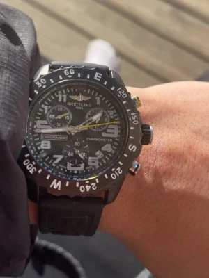 Svart Breitling Endurance Pro klocka - Säljer en svart Breitling Endurance Pro klocka med sportig design. Klockan har svart gummiband, stor boett med tydliga vita siffror och detaljer, samt flera urtavlor och gul sekundvisare. Perfekt för dig som gillar stilrena accessoarer med funktion.