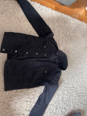marinblå jeansjacka från Only & Sons - Snygg marinblå jeansjacka från Only & Sons i storlek S. Klassisk modell med silverfärgade knappar, två bröstfickor med lock och raka sömmar. Perfekt för dig som vill ha en stilren och enkel look till vardags.