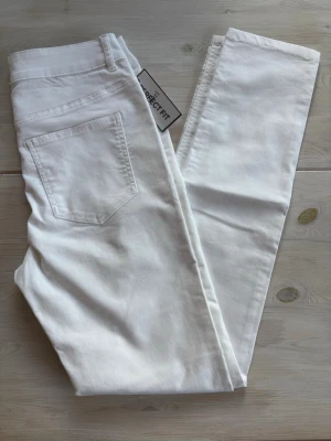 Vita skinny jeans med hög midja - Säljer ett par vita skinny jeans med hög midja och klassiska fem fickor. Jeansen har stretchigt material för skön passform och raka benslut. Perfekta till en trendig och clean look. Helt nya! 