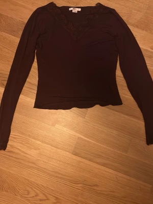 Vinröd långärmad topp med spets. Pris kan diskuteras! - Vinröd långärmad topp med v-ringning och fina spetsdetaljer vid halsringning och ärmslut. Figurnära passform och mjukt material som känns skönt mot huden. Perfekt för dig som gillar stilrena plagg med en twist. Men har dock slitningar längst ner på armarna. 