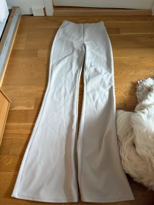 Beige utsvängda leggings XS - Snygga beige leggings med utsvängda ben i stretchigt material. Perfekta för dig som gillar en trendig och bekväm look. Passar till många olika stilar och är superenkla att matcha med både sneakers och boots.