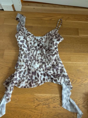 Leopardmönstrad omlottopp från J'aime - Säljer en leopardmönstrad omlottopp från J'aime i storlek S/M. Toppen har tunna axelband, v-ringning och knytband i sidan. Materialet är lätt och luftigt, perfekt för varma dagar. Snyggt fall och trendig look!