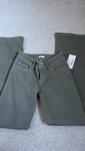 Olivgröna bootcut jeans från Nelly - Helt nya med prislapp kvar, nypris 699kr💞Snygga olivgröna jeans från Nelly med bootcut-modell och dubbla knappar i midjan. Jeansen har klassiska fem fickor och kontrastsömmar. Perfekta för dig som vill ha en trendig och avslappnad look.