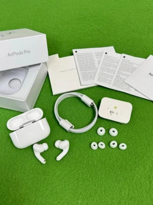 Apple AirPods Pro 2 trådlösa hörlurar - Säljer ett par vita Apple AirPods Pro med laddningsetui, extra silikonpluggar och laddkabel. Hörlurarna har en stilren och kompakt design i blank plast och levereras med originalförpackning och manualer. Perfekta för dig som vill ha grymt ljud och smidig anslutning till din iPhone.