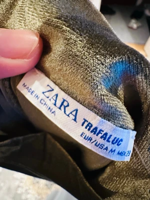Olivgrön sammetsklänning Zara - Säljer en olivgrön sammetsklänning från Zara Trafaluc. Klänningen har lång ärm och en mjuk, glansig finish som ger en lyxig känsla. Perfekt för dig som vill sticka ut med en unik färg och skön passform.