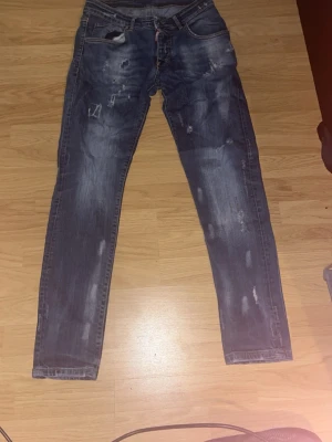 Dsquared2 Jeans blå - Säljer ett par blå skinny jeans med slitningar och distressed detaljer. Jeansen har klassisk femficksmodell, dragkedja och knapp framtill samt kontrastsömmar. Materialet är denim med en tvättad look och slitna partier för en trendig stil.
