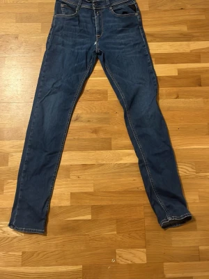 Blå skinny jeans från Replay - Säljer ett par blå skinny jeans från Replay med klassisk femficksmodell och snygga kontrastsömmar. Jeansen har normal midja och dragkedja med knapp. Perfekta för dig som gillar en smal passform och tidlös denimstil. Pris kan diskuteras.
