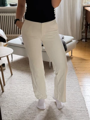 Vida vita kostymbyxor från Stockh LM - Säljer ett par stilrena vita kostymbyxor med raka, vida ben och hög midja. De är i storlek 36. Jag har vanligtvis S/M och är 177cm lång. Materialet är mjukt och stretchigt, perfekt för en clean och modern look.