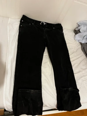 Svarta vida jeans med uppvik - Säljer ett par svarta jeans med bred passform och uppvikta benslut. Klassisk femficksmodell med knapp- och dragkedjegylf. Jeansen har en avslappnad look och är perfekta för dig som gillar en loose fit-stil. W32L32