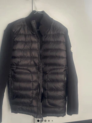 Svart pufferjacka från Moncler - Säljer en svart pufferjacka från Moncler med quiltad front och släta ärmar. Jackan har dragkedja framtill, ståkrage och två sidofickor med dragkedja. Klassisk Moncler-logga på ärmen och innerfoder med serietidningsmönster.
