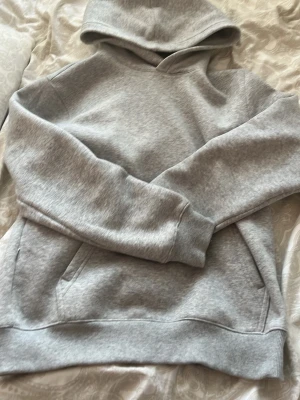 helt ny grå hoodie  - En enkel och stilren ljusgrå hoodie med huva och stor magficka. Tillverkad i mjukt sweatshirtmaterial och har ribbade muddar vid ärmar och nederkant. Perfekt för en avslappnad och bekväm stil.