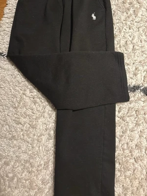 Svart hoodie med vit Polo-logga - Snygg svart hoodie från Polo Ralph Lauren med den klassiska vita broderade loggan på bröstet. Hoodien har en avslappnad passform och är tillverkad i mjukt material som passar perfekt till en chill vardagsstil.