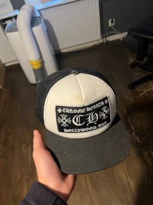 Chrome Hearts truckerkeps svart/vit - Säljer en svart och vit truckerkeps från Chrome Hearts  Kepsen har mesh på sidorna och justerbar snapback. Perfekt för dig som gillar streetwear och vill sticka ut. Kepsen har ett litet brunt märke på framsidan, men det är ingenting man tänker på riktigt. Pris kan diskuteras.