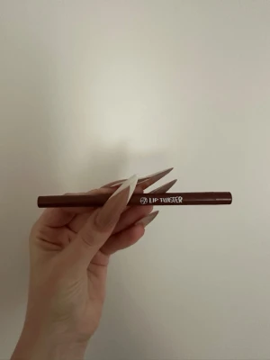 Brun läppenna Lip Twister - Snygg brun läppenna från Lip Twister med klassisk pennform. Perfekt för att definiera och forma läpparna med precision. Pennan har en smidig spets och är enkel att applicera för ett jämnt resultat.