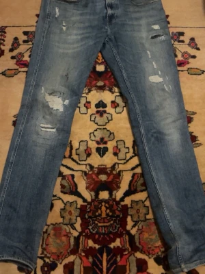 Blå slitna jeans från Replay - Säljer ett par blå jeans från Replay med slitningar och distressed detaljer på både fram- och baksida. Jeansen har klassisk femficksmodell, normal midja och raka ben. Perfekta för en avslappnad och trendig look. Obs! Dom är lite smutsiga men det går säkert bort i tvätten men det är inget jag kan lova! Därav priset. Storlek 31/32 