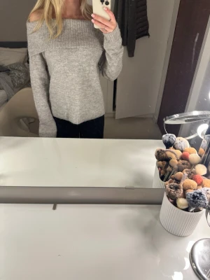 Ljusgrå off shoulder stickad tröja - Säljer en ljusgrå stickad tröja med off shoulder-modell och bred ribbad kant upptill. Tröjan har långa ärmar och är mjuk och skön, perfekt för kyliga dagar. Passar dig som gillar en avslappnad men ändå trendig stil. Storlek 158-164 men sitter som en xs
