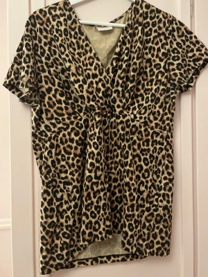 Leopardmönstrad tröja  - Säljer en leopardmönstrad omlottopp med korta ärmar och v-ringning. Skulle säga att tröjan är mer som L, men bysten är mer XL. Köpt second hand 
