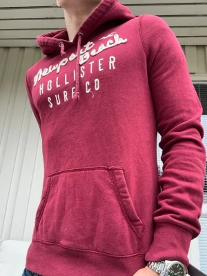 Vinröd Vintage hoodie från Hollister - En av de snyggaste hollister hoodies jag lagt ögat på🤩 Perfekt nu till hösten🍁Inga defekter, de snygga slitningarna på texten kommer från fabrik🙌 En riktigt snygg röd/ vinröd färg🤝 En av de fräschaste hoodies av hollister jag sett🙌  L på lappen men passar S. Längd från axel: 60cm🤩