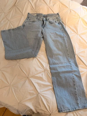 Straight midwaist jeans - Säljer ett par ljusblå jeans med straight passform och midwaist. Klassisk femficksmodell i denim med knappgylf och bälteshällor. Perfekta till en avslappnad stil och passar till det mesta i garderoben.