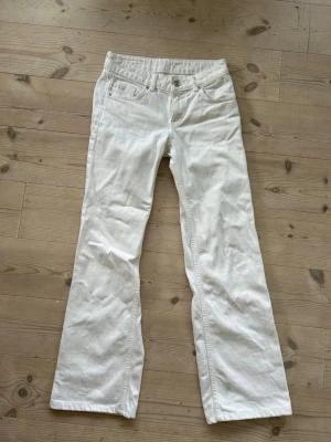 Vita vida jeans - Säljer ett par vita vida jeans med klassisk femficksmodell och låg midja. Perfekta för dig som vill ha en clean och fräsch look till vardags. Jeansen är från Zara i storlek 32, men uppsydda hos skräddare till 74 cm i innerbneslängden. 