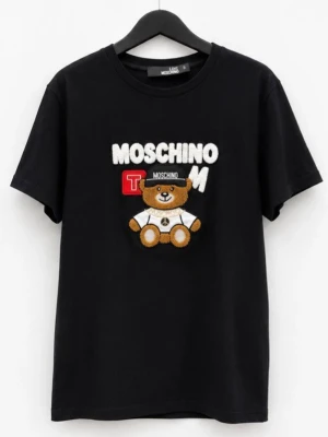 Svart Moschino t-shirt med björn - Svart t-shirt från Moschino med ett broderat motiv av en söt björn och texten MOSCHINO på bröstet. Klassisk rund hals och korta ärmar. Tillverkad i mjuk bomull för en bekväm känsla. Perfekt för dig som gillar statement-plagg med lekfull touch.