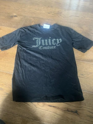 Svart Juicy Couture t-shirt - Snygg svart t-shirt från Juicy Couture med glittrande text framtill. Ett litet hål på baksidn som knapt syns💞