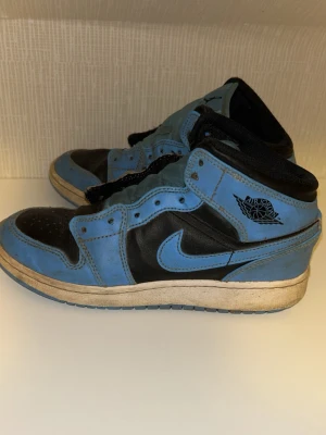 Jordan 1 Mid strl 37,5 - Säljer blå svarta Jordan 1 mid sneakers i storlek 37,5. Skorna är i acceptabelt skick men man kan tvätta med vissa produkter. Som man ser på bilden kommer skorna utan snöre men det är något man kan sätta i. Hör av er vid frågor.
