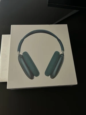 AirPods Max  - Snygga over-ear hörlurar i blått med mjuka öronkuddar och justerbart huvudband. Hörlurarna har en modern design med aluminiumkåpor och mesh-material på insidan av bågen. Perfekta för musik, gaming eller film.