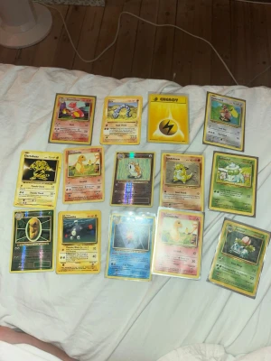 Nostalgi pokemon kort - Säljer en gammal samling Pokémonkort med blandade generationer och typer. Innehåller både vanliga och holografiska kort, bland annat Electabuzz, Sandshrew, Starmie och en gul Lightning Energy. Perfekt för dig som vill utöka din samling eller börja spela Pokémon TCG.