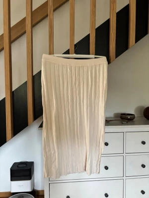 Beige midikjol från Pernilla Wahlgren - Säljer en beige midikjol från Pernilla Wahlgren. Kjolen har ribbad midja och ett plisserat fall som ger en snygg och avslappnad look. Perfekt att styla med en enkel topp eller stickad tröja.